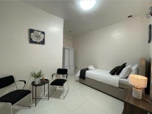 a bedroom with a bed and chairs and a table at Cresta Dormitory in Dumaguete