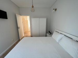 biała sypialnia z dużym łóżkiem i drzwiami w obiekcie Custódio Ocean View w mieście Praia de Mira
