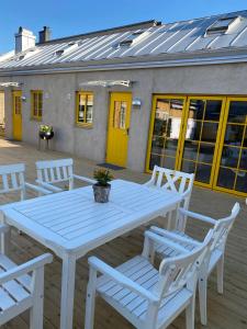 una mesa blanca y sillas en una terraza con un edificio en Casa Annie & Nadja - Toppmodernt centralt i Borgholm en Borgholm