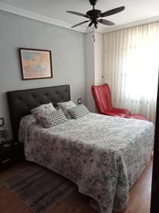 a bedroom with a bed and a red chair at Confortable y luminoso apartamento in Valladolid