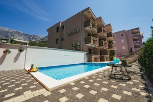 a swimming pool with a table in front of a building at Family-friendly apartments with swimming pool Promajna, Makarska - 6849 in Promajna