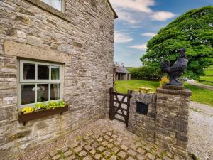 una casa de piedra con una estatua de pájaro a un lado. en Sweet knoll cottage, en Buxton