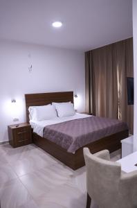 a bedroom with a large bed and a chair at Hamptons Village Apartments Ada Bojana in Ulcinj