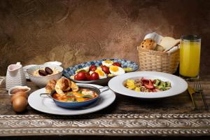 a table with plates of breakfast food and a glass of orange juice at Hotel Boutique Casa Hendaus - Adults Only in San Andrés
