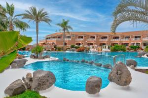 een zwembad van het resort met rotsen en palmbomen bij Sol Sun Beach in Adeje