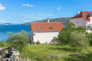 a house with a red roof on a hill next to the water at Apartments by the sea Poljica, Trogir - 10353 in Marina