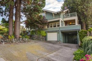 a large green house with a garage and trees at Serene Tacoma Home with Furnished Deck and Views! in Tacoma