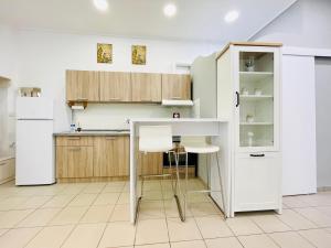 een keuken met witte kasten en een tafel en stoelen bij Ithaca: Διαμέρισμα με αυτόνομη είσοδο. in Thessaloniki