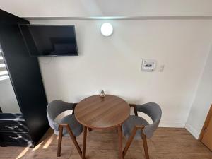 mesa de comedor con 2 sillas y TV en TinyApartments - estudio pleno centro Concepción, en Concepción