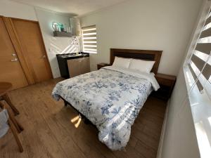 1 dormitorio con 1 cama con manta azul y blanca en TinyApartments - estudio pleno centro Concepción en Concepción