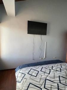 里奧班巴的住宿－CasaHogar Apartamento，卧室配有一张床铺,墙上配有电视