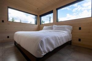 a bedroom with two windows and a bed with white sheets at Le Nørr - Maelström (CITQ #302901) in Lac-Beauport