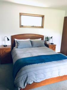 a bedroom with a large bed with blue sheets and a window at Snowcapped Peaks in Mount Beauty