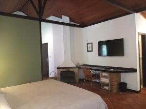 a bedroom with a bed and a desk with a television at Canto do Bosque - Chalé Sabiá com hidromassagem in Araras Petropolis