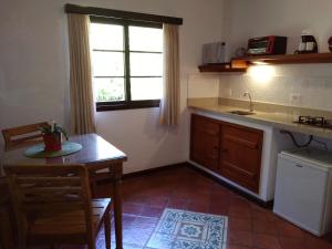 uma cozinha com uma mesa, um lavatório e uma janela em Canto do Bosque - Chalé Sabiá com hidromassagem em Araras, Petrópolis