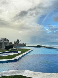 a resort swimming pool with the ocean in the background at Paraíso a beira-mar na praia de Búzios/RN in Nísia Floresta