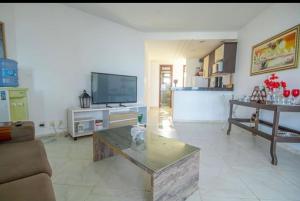 een woonkamer met een bank en een tv bij Paraíso a beira-mar na praia de Búzios/RN in Nísia Floresta