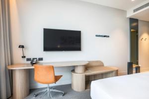 a hotel room with a desk and a tv on the wall at Holiday Inn Werribee, an IHG Hotel in Werribee