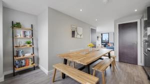 ein Esszimmer mit einem Holztisch und Bänken in der Unterkunft Host & Stay - The Baltic Penthouse 2 in Liverpool