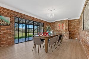 a dining room with a brick wall and a table and chairs at The Weltara - 6 bedrooms House Near Anna Bay in Williamtown