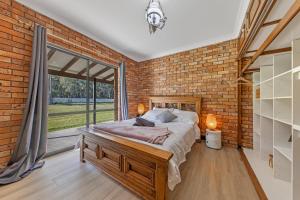 una camera da letto con pareti in mattoni, un letto e una grande finestra di The Weltara - 6 bedrooms House Near Anna Bay a Williamtown