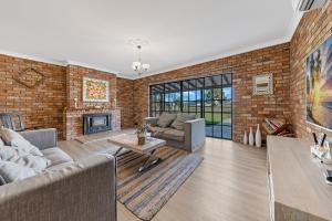 uma sala de estar com uma parede de tijolos em The Weltara - 6 bedrooms House Near Anna Bay em Williamtown