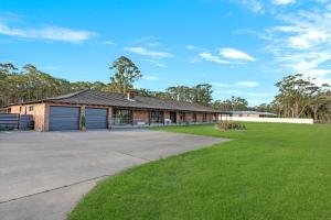 a house with a garage and a grass yard at The Weltara - 6 bedrooms House Near Anna Bay in Williamtown