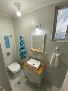 uma casa de banho com um WC, um lavatório e um espelho. em Apartamento Guarujá Pitangueiras 50 metros Praia/3 Dormitórios/Vista do Mar, Sol da manhã no Guarujá