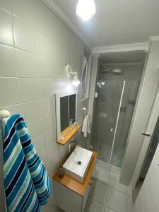 La salle de bains est pourvue d'un lavabo et d'une douche avec un miroir. dans l'établissement Apartamento Guarujá Pitangueiras 50 metros Praia/3 Dormitórios/Vista do Mar, Sol da manhã, à Guarujá
