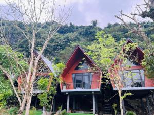 ein rotes Haus mit einem Balkon im Wald in der Unterkunft Lèn Chùa Ecostay in Phong Nha