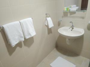 a white bathroom with a sink and towels at Rayan Hotel Suites in Amman