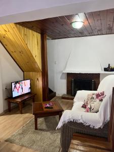 salon z kanapą i telewizorem w obiekcie Chalé Modesto w mieście Campos do Jordão