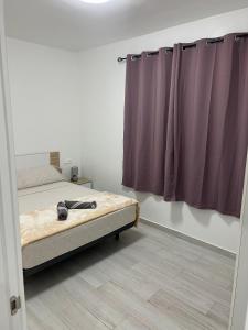 a bedroom with a bed and purple curtains at CASA PARAISO 3 in Corralejo