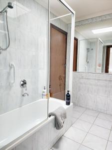a white bathroom with a shower and a tub at Sandy Shores Estate- Long Island in Frankston