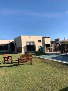 two benches sitting in the grass in front of a house at Casa con piscina en Maipú, Mendoza in Maipú