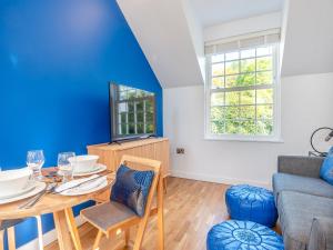 Gunns Loft في Smallburgh: غرفة طعام مع طاولة والجدار الأزرق