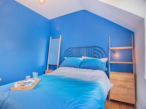 a blue bedroom with a bed with a blue wall at Gunns Loft in Smallburgh