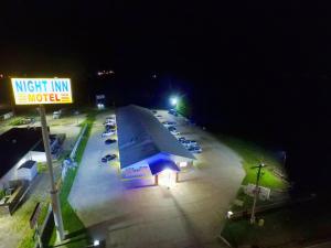 a parking lot with cars parked next to a night inn motel at Night Inn in Sweet Springs