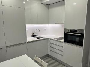 a white kitchen with a sink and a microwave at Apartamento Brisa do Mar in Sesimbra +5 photos