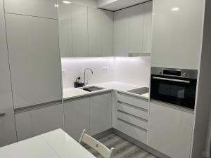 a white kitchen with a sink and a microwave at Apartamento Brisa do Mar in Sesimbra