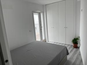 a white bedroom with a bed and a window at Apartamento Brisa do Mar in Sesimbra