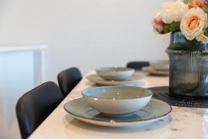 una mesa con tazones y un jarrón con flores en Mega Style Apartments Melbourne Square en Melbourne
