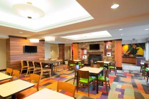 a restaurant with tables and chairs and a fireplace at Fairfield Inn & Suites by Marriott State College in State College