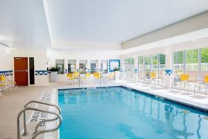 a swimming pool with yellow chairs and tables in a building at Fairfield Inn & Suites by Marriott State College in State College