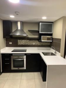 a kitchen with a stove and a sink and a microwave at Puerto Santa Ana, Torres Bellini, 2 dormitorios, Parqueo in Guayaquil