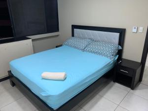 um quarto com uma cama com lençóis e almofadas azuis em Puerto Santa Ana, Torres Bellini, 2 dormitorios, Parqueo em Guayaquil