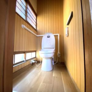 a bathroom with a toilet in a wooden wall at Abuden in Kumano for women and families 女性と家族専用の宿 in Kumano