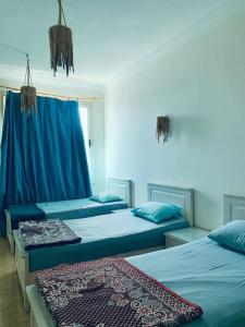 a room with two beds with blue sheets at Luna House Lighthouse in Dahab