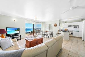 a living room with a couch and a tv and a kitchen at Bayview Towers in Nelson Bay