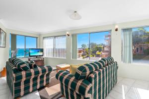 a living room with two chairs and a television at Bayview Towers in Nelson Bay